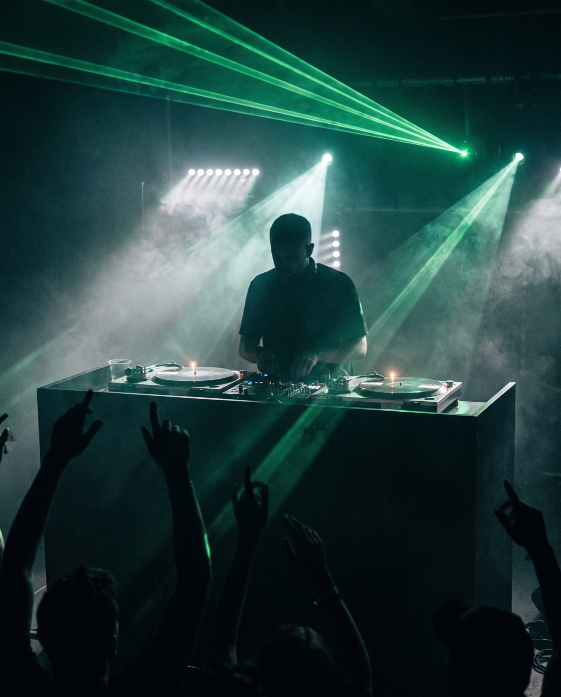 DJ at the booth under green lasers